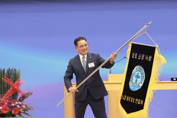 회기를 이양받은 신임회장 문만수 장로가 기를 흔들고 있다.